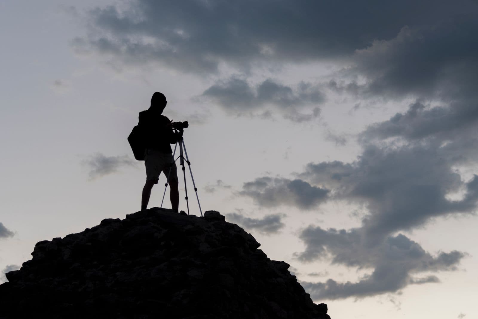 A lone photographer at golden hour capturing a mountain landscape