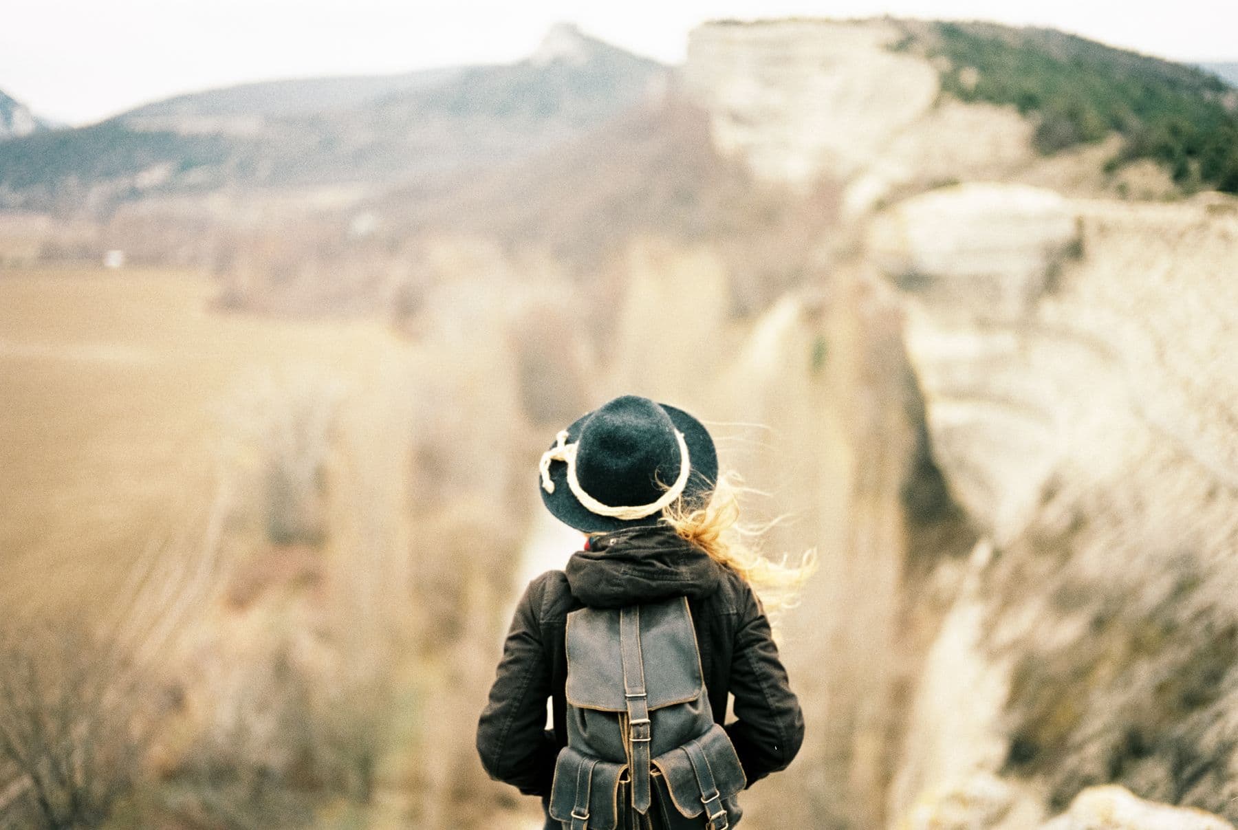 A traveler with a backpack looking out over a mountain valley